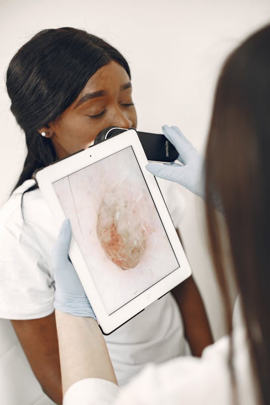 Dermatolog hastanın cildini dijital cihazla inceliyor